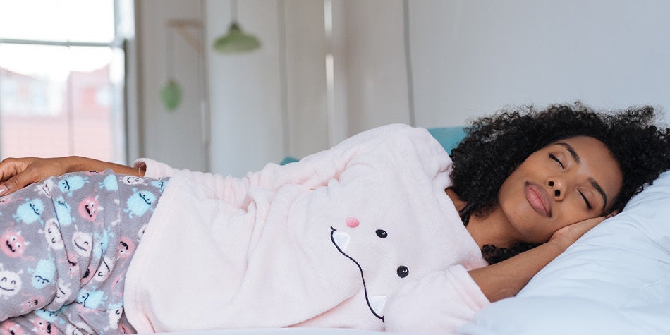 Women in pink pajamas sleeping peacefully in bed.