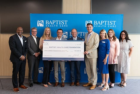 Group of people holding big check. J.D. Myers, II, SVP, East Region Manager, Cox Communications; Perley McBride, EVP & CFO, Cox Communications; Kara Bullock, Asst. VP, James M. Cox Foundation; Mark Greatrex, President, Cox Communications; Mark Faulkner, President & CEO, Baptist Health Care; David Deliman, Market VP, Cox Communications; Kristin Longley, East Region Director of Public Affairs, Cox Communications; Heather Moorer, Development Director, Baptist Health Care; Stephanie Federico, East Region VP Government & Public Affairs, Cox Communications