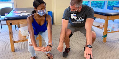 Physical therapist performing stretching exercise with student-athlete. 