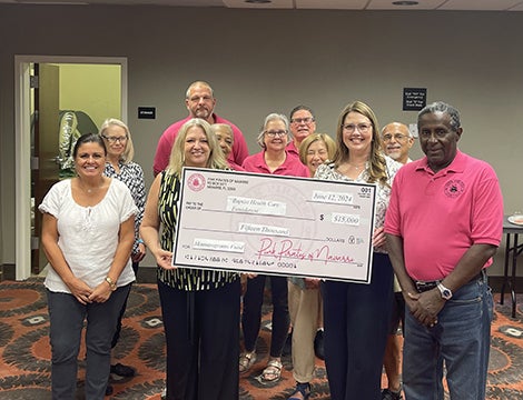 Group of people wearing pink and holding a big check