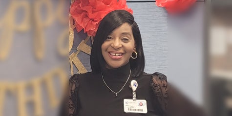 Veronica, a patient representative and black female poses with badge near her office