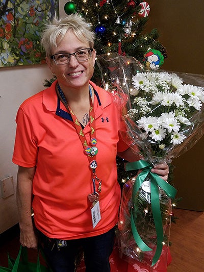 Kelly Godwin in orange shirt holding daisy bouquet