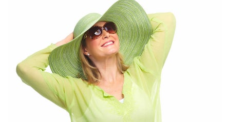 Woman wearing green had and sunglasses smiling.