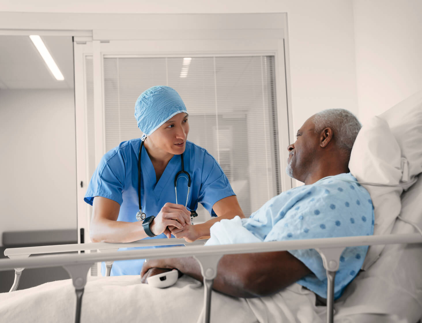 Patient sitting in hospital bed talking with healthcare professional