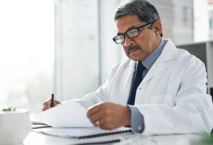 Doctor with glass looking down at desk