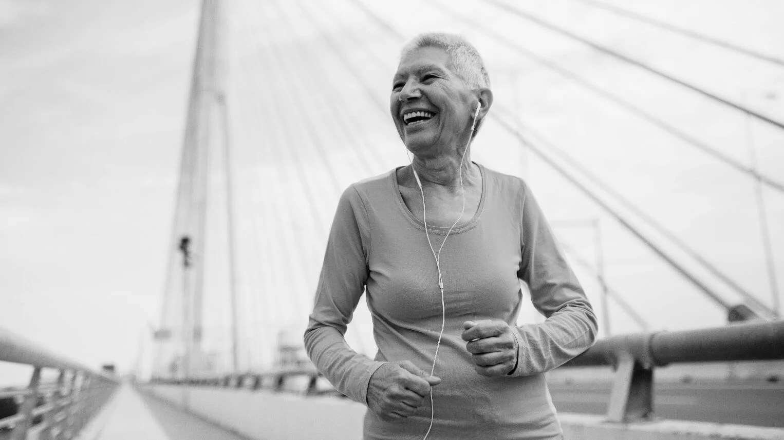 Elderly woman jogging on bridge