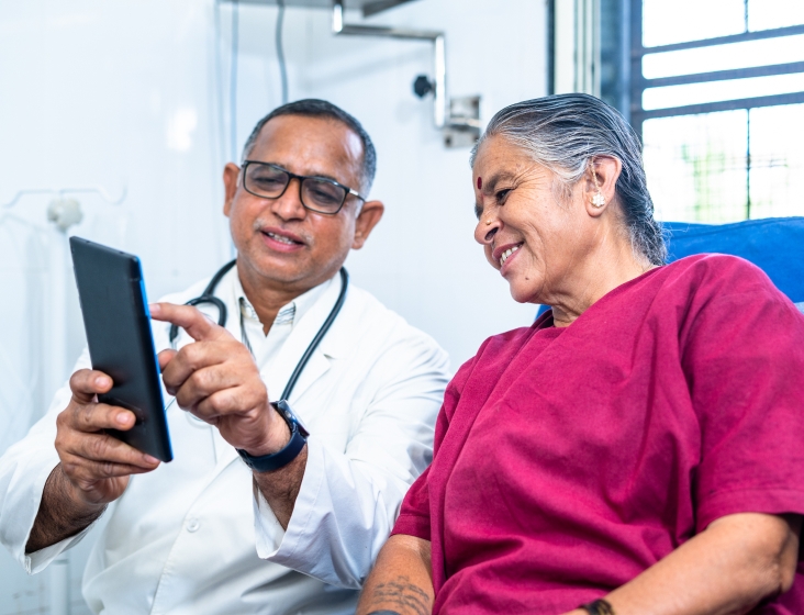 Patient sitting in hospital bed talking with healthcare professional