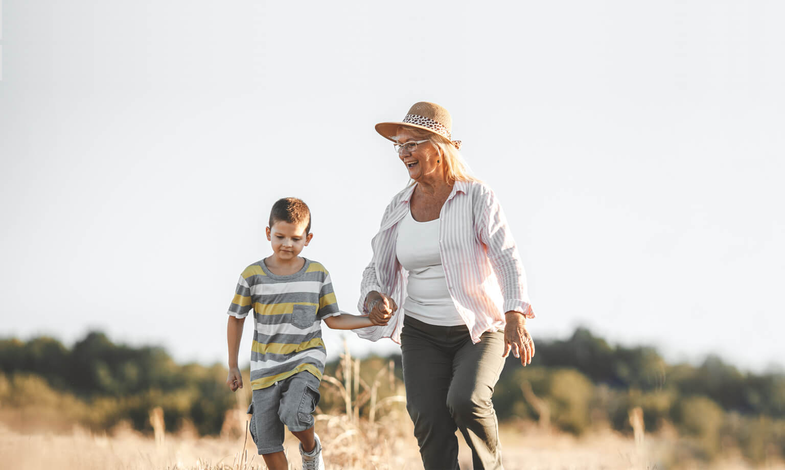 Grandma and grandson walking through field