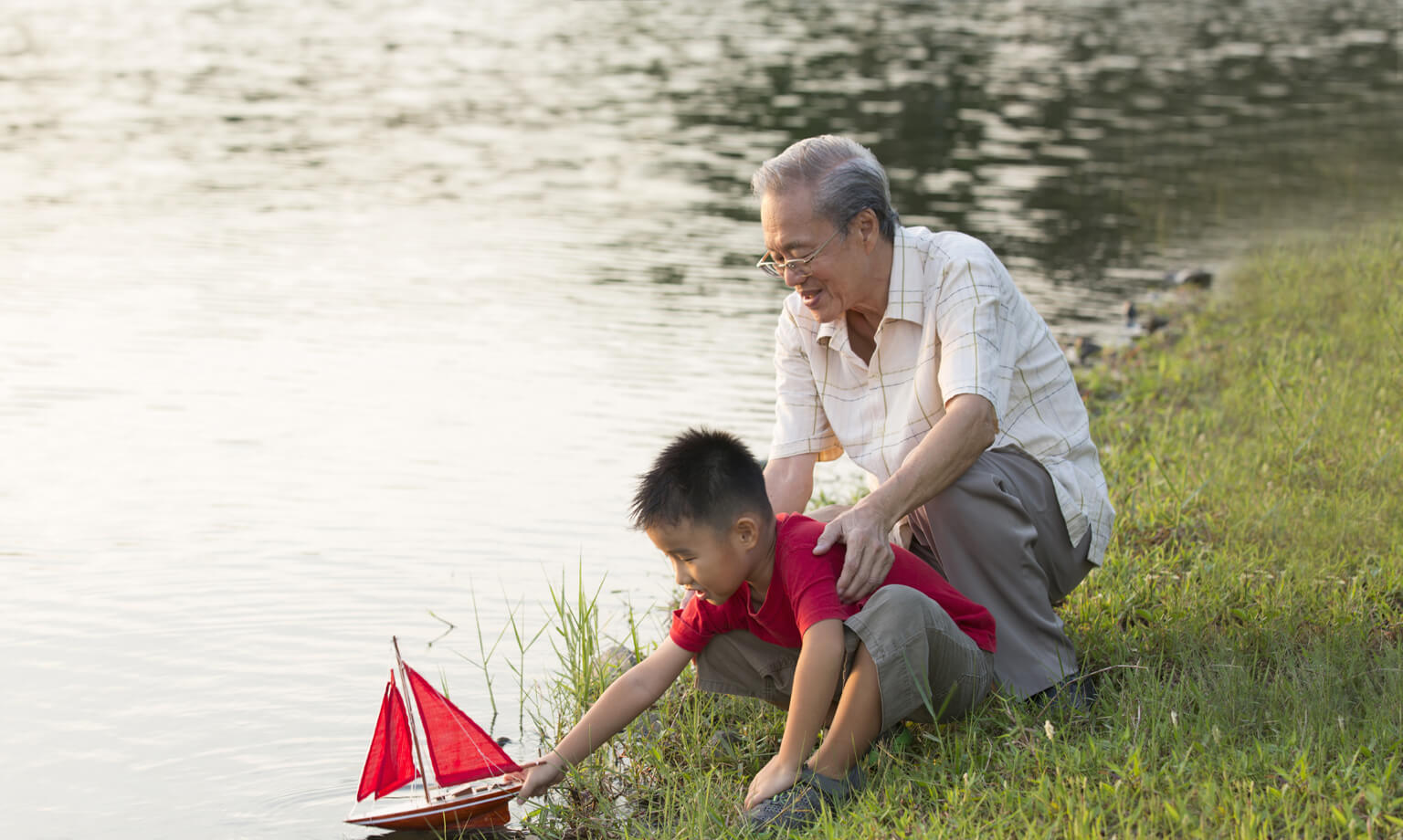 Grandpa with grandson at the lake with toy boat