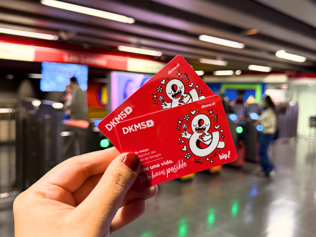 Mano sosteniendo dos tarjetas Bip conmemorativas de DKMS en una estación de Metro de Santiago Mano sosteniendo dos tarjetas Bip conmemorativas de DKMS en una estación de Metro de Santiago