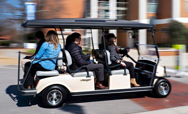 A group of people ride a Club Car Villager.