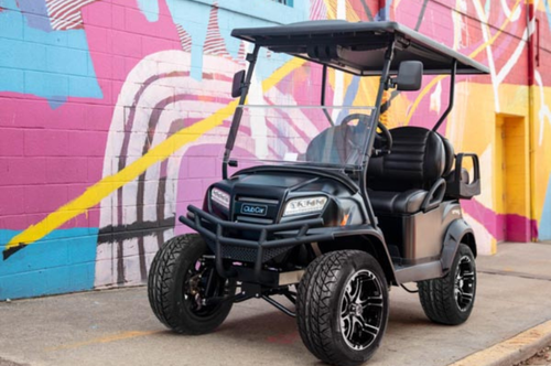 A matte black Eclipse Special Edition Club Car golf cart parked in front of a colorful street mural.