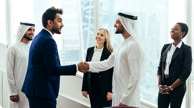 smiling-colleagues-looking-businessmen-shaking-hands-meeting-office 1.png