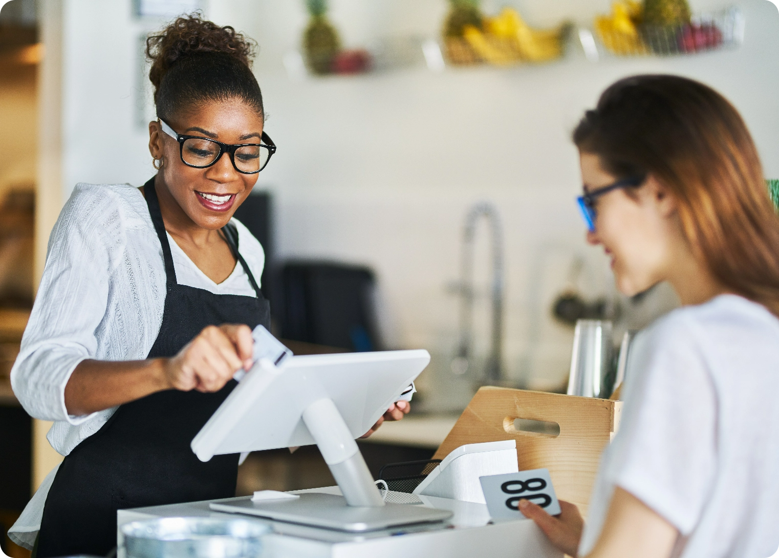 Customer standing at the register of a business while the employee is accepting and entering payment into her point of sale system