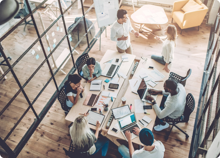 Arial view of an office conference room table with workers and computers surrounding the table