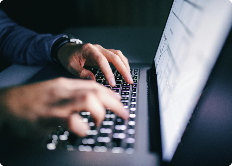 fingers typing on laptop with dark background