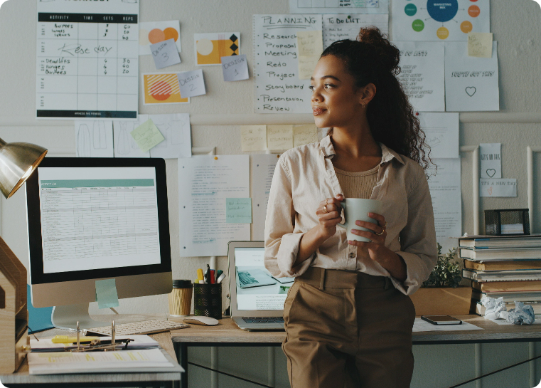 Non profit professional standing in an office with coffee looking out the window
