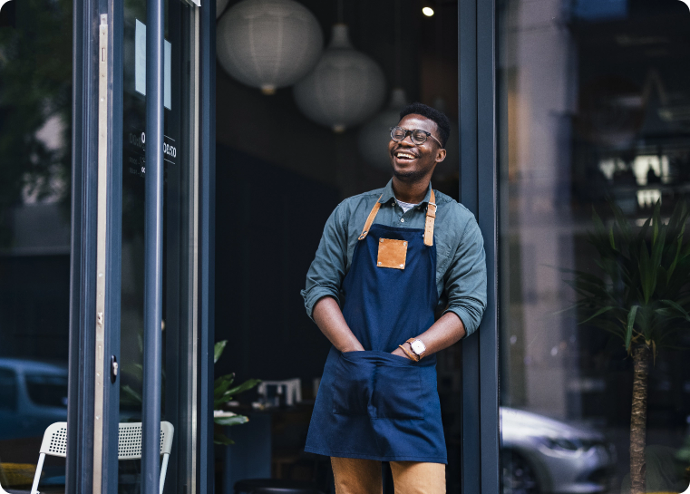 Worker standing outside of a business smiling and looking out onto the street