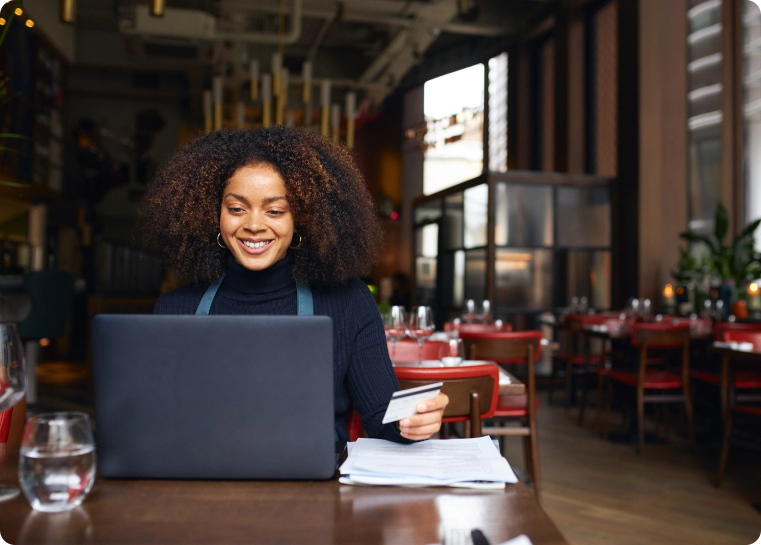 Woman on her laptop with credit card smiling