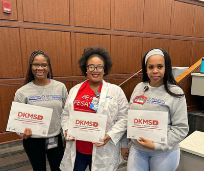 Three students from The University of Memphis Student Nursing Association holding DKMS packets
