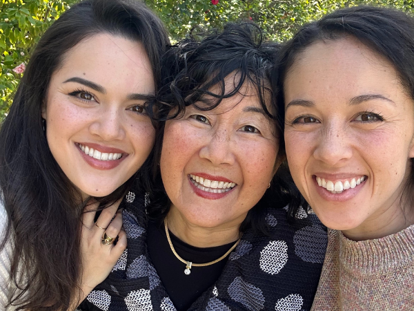 Emi Grannis on the left, hugging her mom. Trish (Mama G) Grannis is in the middle with her daughter, Kina Grannis standing up against her on the right.  