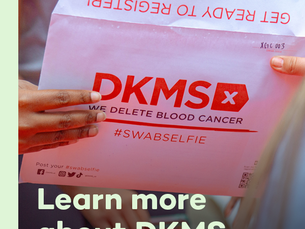 Close up of two individuals holding a DKMS registration packet with the text overlay, "Learn more about DKMS"