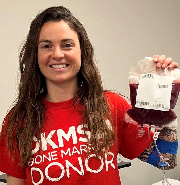 DKMS donor, Aimee, holding her stem cells in her DKMS donor shirt