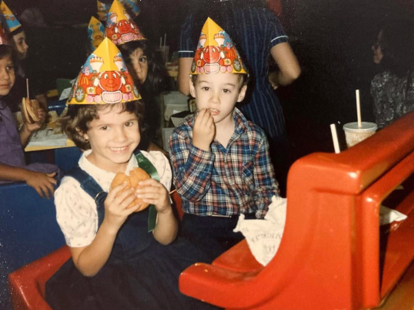 Alyson and Michael as young kids wearing party hats and eating burgers
