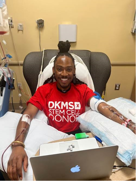 DKMS Blood Stem Cell Donor, Deonte, sitting in a chair donating his stem cells while smiling wearing a DKMS donor shirt. 