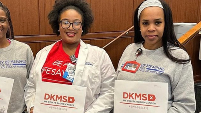 Three nursing students from the University of Memphis smile while holding DKMS registration packets. 