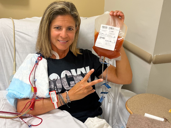 DKMS Donor Alyson holding her blood stem cell donation in a Rocky shirt