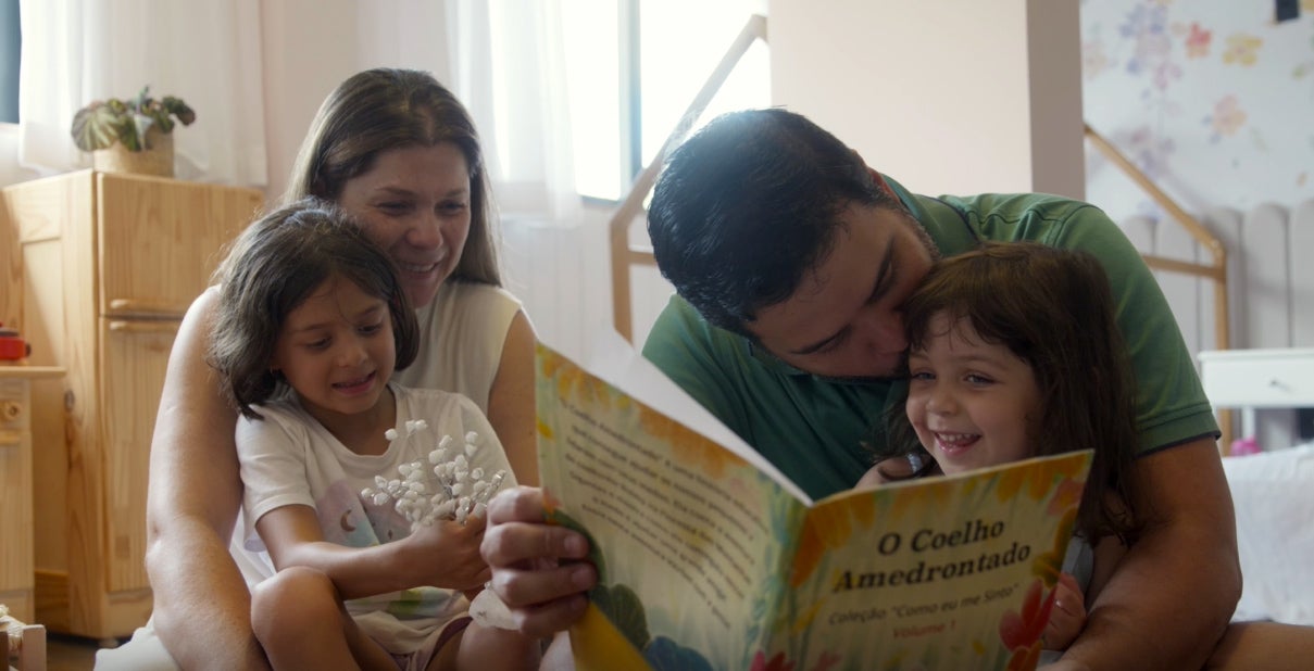 Leonardo Lima reading to his kids with his wife at home. 