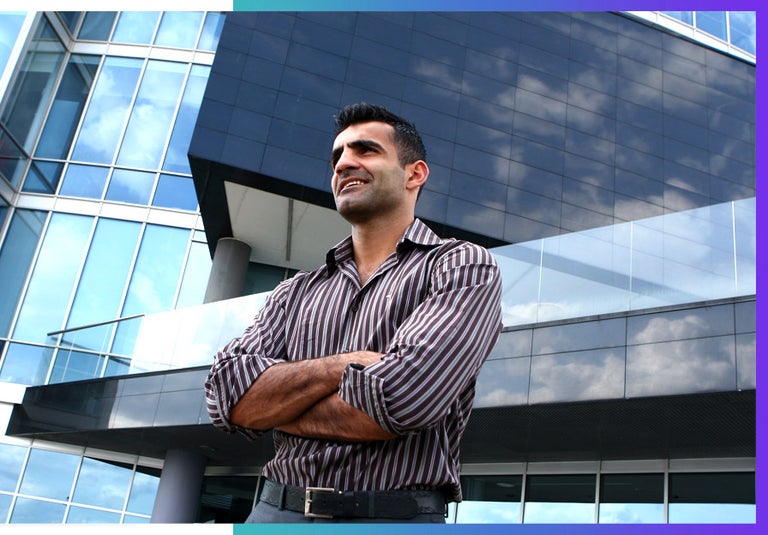 A man stands in front of a building he built. AI automation architect. 