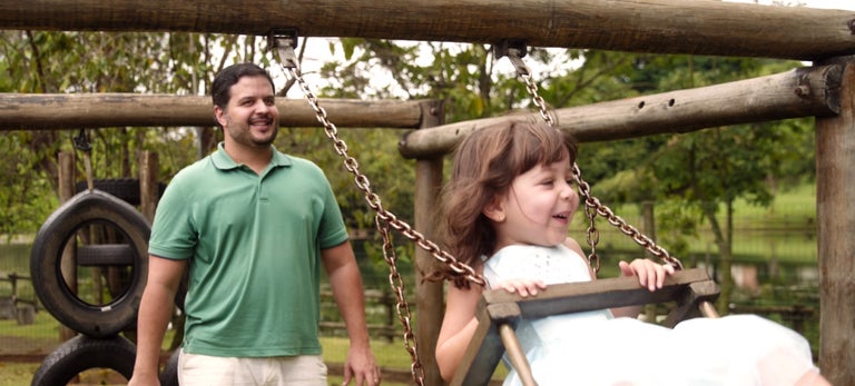 Leonardo pushing his daughter on the swings outside, Brazil. 