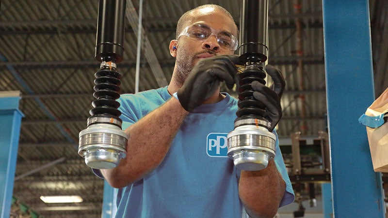 PPG technician wearing a blue PPG t-shirt monitoring and cleaning coating machinery.