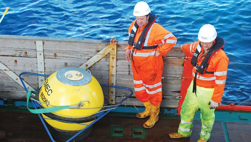 Two technicians with life jackets on stood on the dock of PPG's live marine test site at the European Marine Energy Centre [EMEC].