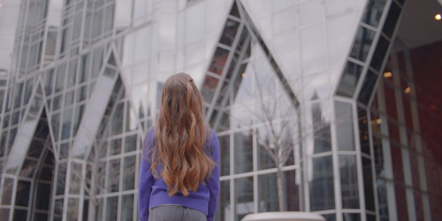 Young girl wearing purple sweat looking up at PPG's headquarters in Pittsburgh, Pennsylvania.