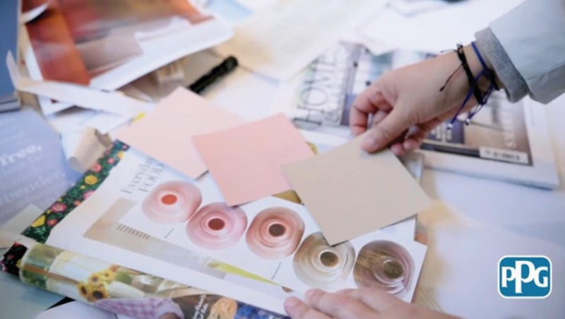 PPG color stylist holding color swatches against a home styling magazine.