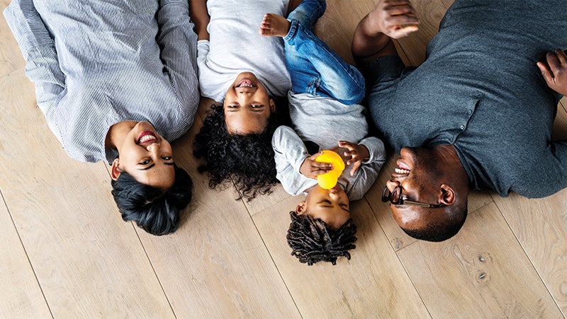 Family of floor lying down on a light wood-stained floor.