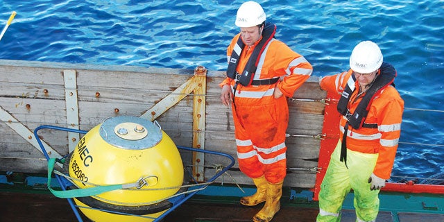 Two technicians with life jackets on stood on the dock of PPG's live marine test site at the European Marine Energy Centre [EMEC].