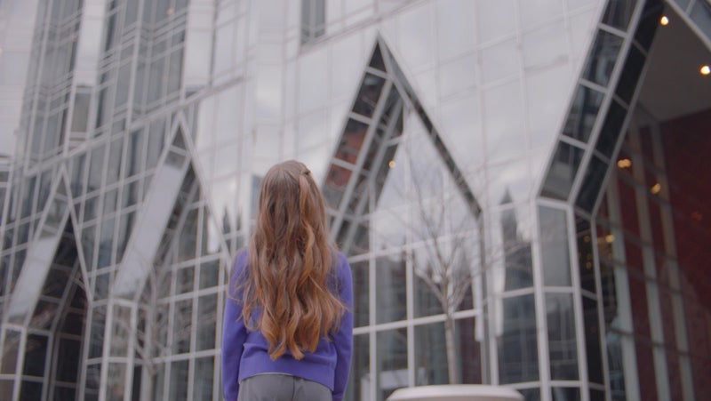 Young girl wearing purple sweat looking up at PPG's headquarters in Pittsburgh, Pennsylvania.