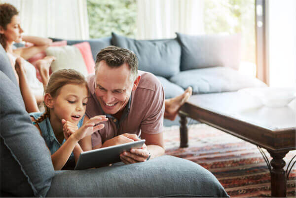 Father and daughter on couch with tablet