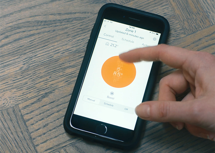 A hand touching a smart phone screen with Hive smart home app