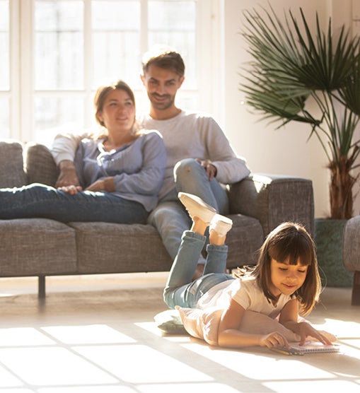 Couple sitting on sofa while daughter players on the floor