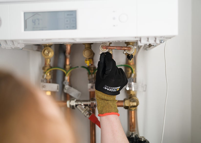 An engineer's hand fixing boiler pipes.