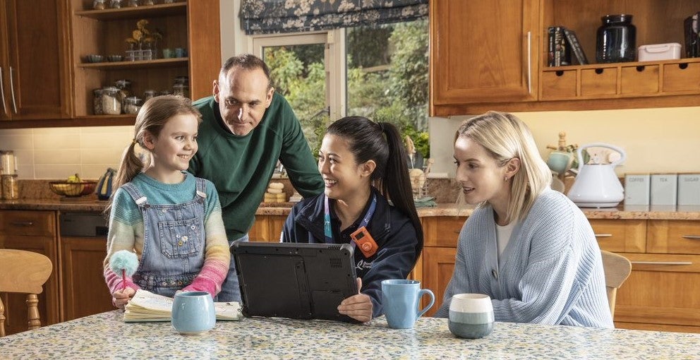 Service engineer with family at kitchen table.
