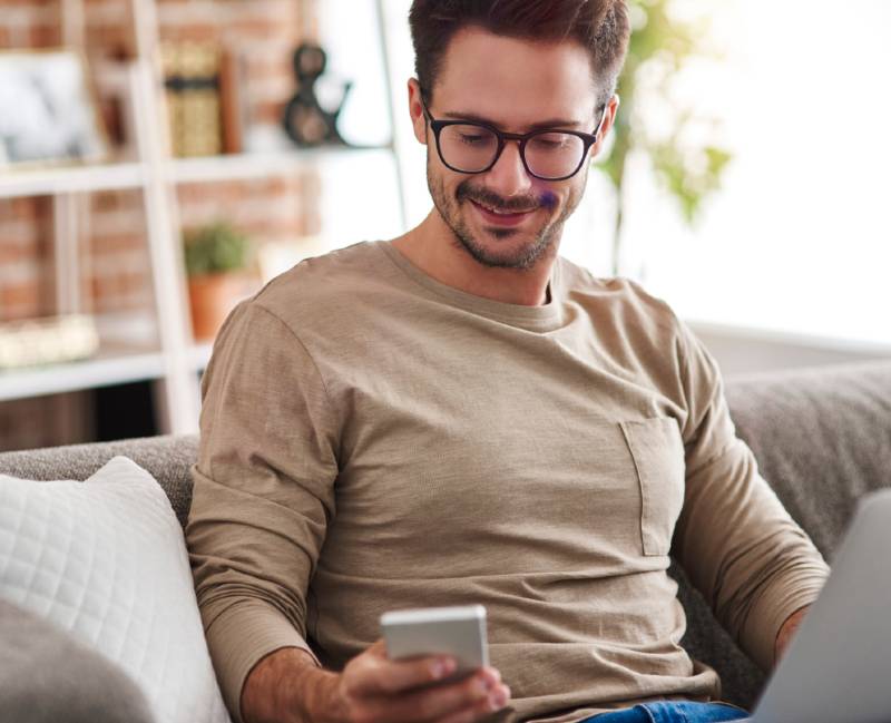 Man on couch with laptop and phone