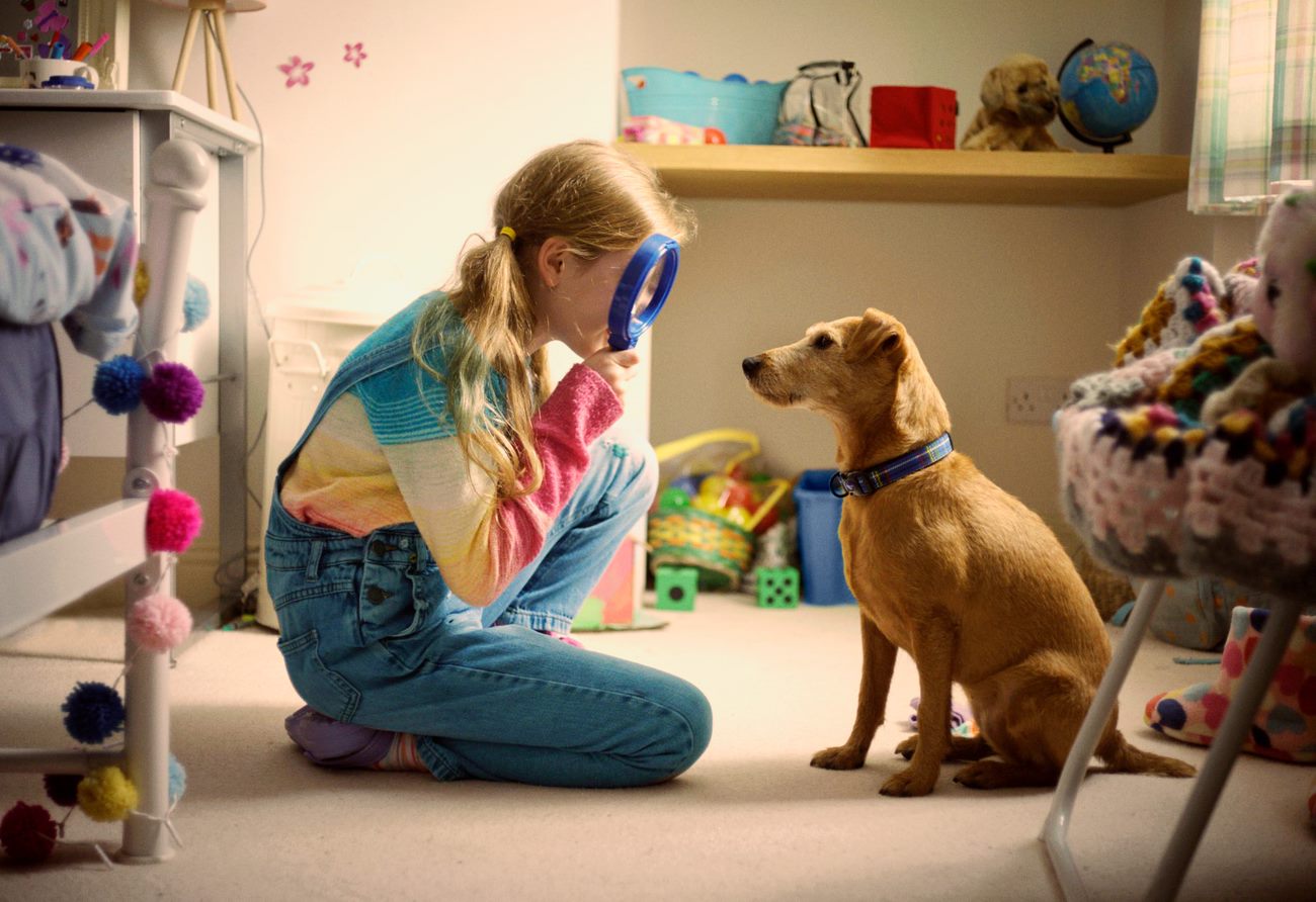 Little girl looking at dog with magnifying glass