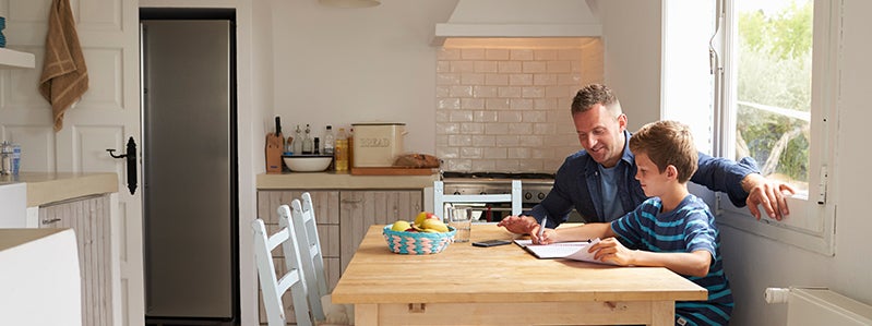 Father and son doing homework at kitchen table
