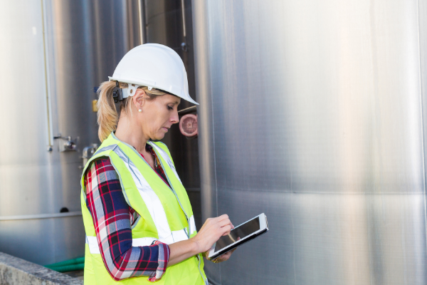 Woman with hard hat and high vis jacket working on industrial site